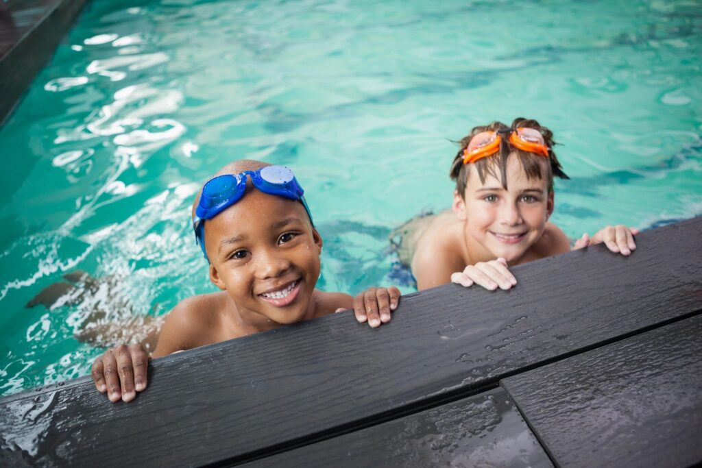 two children in a swimming pool looking up at the camera.